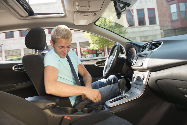 Person putting on seatbelt behind the steering wheel