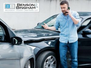 A person standing next to two cars after a collision, talking on the phone, with one vehicle damaged, possibly due to a wrong-way driver in Nevada