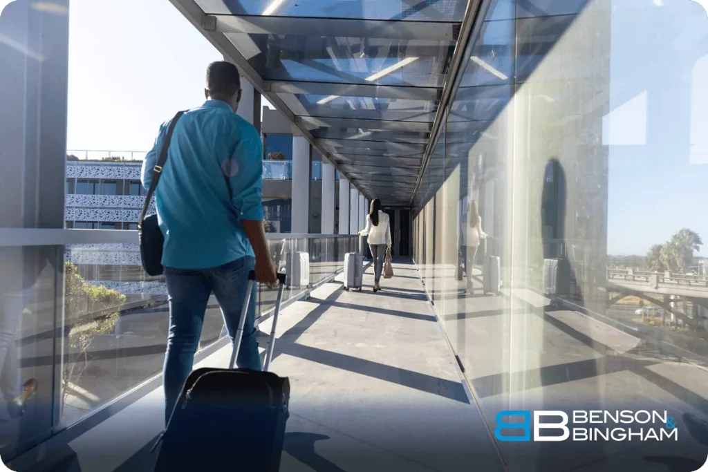Traveler pulling a suitcase through an airport walkway on the way home